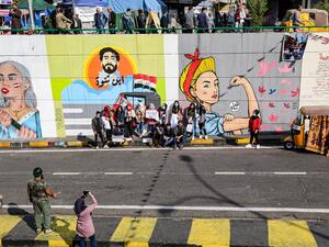 Protesters pose for a picture by graffiti murals during an anti-government demonstration in the Iraqi capital Baghdad's Tahrir Square on November 23, 2019. (SABAH ARAR / AFP)