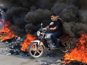 An Iraqi man drives through burning tires in the Shiite Muslim shrine city of Karbala, south of Iraq's capital Baghdad, on November 26, 2019. Since October 1, Iraq's capital and majority-Shiite south have been swept by mass rallies against corruption, a lack of jobs and poor services that have escalated into calls for a complete overhaul of the ruling elite. Mohammed SAWAF / AFP