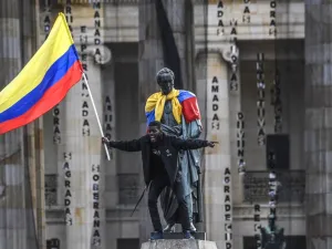 A man waves a national flag atop a statue of the Liberator Simon Bolivar during a protest against the government of Colombian President Ivan Duque in Bogota on November 27, 2019. Protest leaders in Colombia called a new general strike for Wednesday after a meeting with President Ivan Duque made no progress towards ending deadly anti-government demonstrations now in their sixth consecutive day. Juan BARRETO / AFP