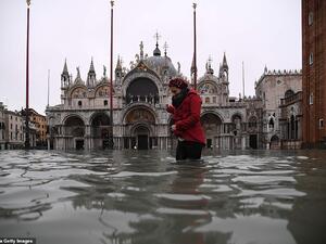 Submerged: A woman crosses the flooded St Mark's Square yesterday morning where Venice's 1,200-year-old basilica (pictured behind her) was flooded by the high tide. (AFP/ File Photo)