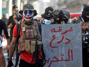 A 23-year-old unemployed Iraqi man, wearing face-paint modeled after DC comic book and film character "The Joker", poses for a picture with a makeshift riot shield bearing text in Arabic reading "Tahrir Shield Division", during an anti-government demonstration in the capital Baghdad on November 22, 2019. (AFP/ File Photo)