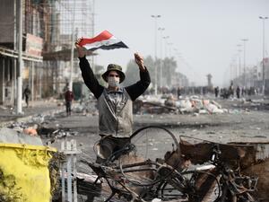 An Iraqi demonstrator carries the national flag in the southern Iraqi Shiite holy city of Najaf (AFP)