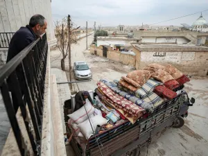 Abu Bilal, a Syrian man from the village of al-Ghadfah in Syria's northwestern Idlib province, watches from a balcony as a truck is being loaded with his belongings on December 1, 2019, before departing from the village towards Azaz in the north of Aleppo province following recent military developments in Idlib. Omar HAJ KADOUR / AFP