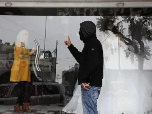 A masked member of the Palestinian Fatah political party tells a woman to close her shop in the southern West Bank city of Hebron after the party called a general strike over Israeli settlement activity in the area, on December 9, 2019. (AFP/ File Photo)