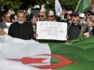 Algerian protesters march with national flags and signs, one in French reading "I will not vote against the future of my country", during a demonstration against the upcoming presidential election, in the capital Algiers on December 10, 2019. RYAD KRAMDI / AFP