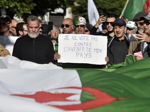 Algerian protesters march with national flags and signs, one in French reading "I will not vote against the future of my country", during a demonstration against the upcoming presidential election, in the capital Algiers on December 10, 2019. RYAD KRAMDI / AFP