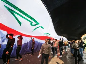 Protesters march with a giant Iraqi national flag during an anti-government demonstration in the capital Baghdad's central Tahrir Square on December 22, 2019.  SABAH ARAR / AFP