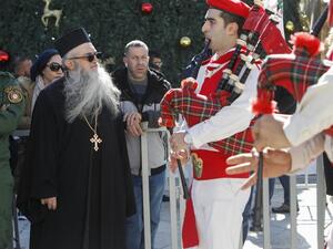 A priest looks at Palestinian scouts performing during a parade at the Manger Square outside the Church of the Nativity in the biblical West Bank city of Bethlehem on December 24, 2019. Pilgrims from around the world gathered today in the biblical city of Bethlehem, revered by Christians as the birthplace of Jesus, to celebrate Christmas in the Holy Land. Musa AL SHAER / AFP