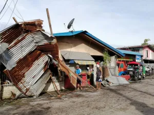 Residents stand next to a house damaged by typhoon Phanfone in Ormoc City, Leyte province in central Philippines on December 25, 2019. Typhoon Phanfone pummelled the central Philippines on December 25, bringing a wet, miserable and terrifying holiday season to millions in the mainly Catholic nation. RONALD FRANK DEJON / AFP