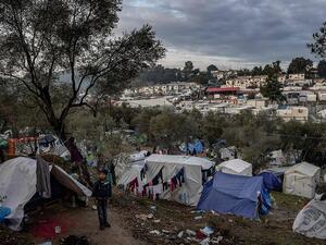 A young boy stands outside a tent at a makeshift camp next to the overcrowded refugee camp of Moria, on the island of Lesbos (AFP)