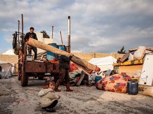 Syrians, among those who fled from government forces' advance on Maaret al-Numan in the south of Idlib prvoince, unload a rolled-up carpet from a truck at a camp for the displaced near the town of Dana in the province's north near the border with Turkey, on December 27, 2019. Aaref WATAD / AFP