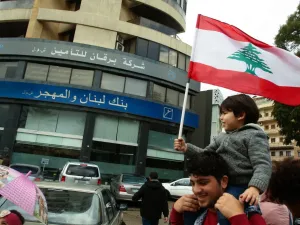 A Lebanese protester carries a child as he takes part in a rally in front of a bank in the southern city of Sidon (Saida) on December 30, 2019 to protest against nationwide imposed restrictions on dollar withdrawals and transfers abroad in an attempt to conserve dwindling foreign currency reserves. (AFP/ File Photo)