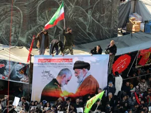 Iranian mourners carry a picture of Iran's Supreme Leader Ayatollah Ali Khamenei (R) granting the Order of Zolfaghar, the highest military honour of Iran, to General Qasem Soleimani, during the latter's funeral procession in the capital Tehran on January 6, (AFP/ File Photo)