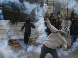 A Palestinian demonstrator uses a slingshot to return a tear gas canister toward Israeli forces during clashes with them following a weekly protest against the expropriation of Palestinian land by Israel, in the village of Kfar Qaddum, in the occupied West Bank on January 10, 2020. JAAFAR ASHTIYEH / AFP