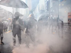 In this picture taken on August 25, 2019, Abby (centre R), 19, and her boyfriend Nick (centre L, holding tongs), 20, react after police fired tear gas during a protest in Tsuen Wan, an area in the New Territories in Hong Kong. ANTHONY WALLACE / AFP