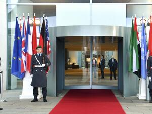 Guards stand next to the flags of the participating countries at the entrance of the German Chancellery in Berlin on January 19, 2020, before the arrival of the participants of the Peace summit on Libya. John MACDOUGALL / AFP