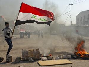An anti-government protester waves an Iraqi national flag at a make-shift roadblock during clashes with security forces in Iraq's southern city of Basra on January 20, 2020. Hussein FALEH / AFP