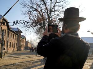  In this file photo taken on December 05, 2019 the face of a visitor is reflected on the screen of his phone as he takes a picture of the main entrance at the Auschwitz German Nazi death camp ahead of German Chancellor Angela Merkel's landmark visit in Oswiecim, Poland. (AFP/ File Photo)
