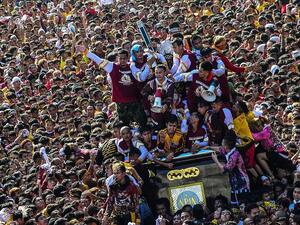 The display of religious fervor by largely poor Filipinos is one of the largest Catholic festivals in the world, and one of Asia's biggest religious events. Pictured: People climb on top of a statue of Black Nazarene as it parades through the streets  (AFP)