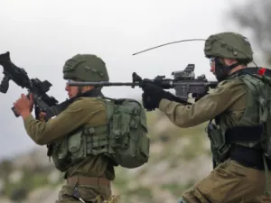 Israeli soldiers hold up their rifles towards Palestinian protesters in the village of Kfar Qaddum, near Nablus in the occupied West Bank (AFP)