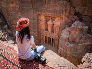 Asian woman traveler sitting on carpet viewpoint in Petra ancient city looking at the Treasury or Al-khazneh, famous travel destination of Jordan and one of seven wonders. (Shutterstock/ File Photo)