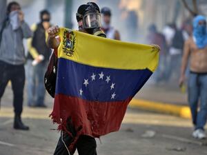 TORN. An anti-government student holds a torn Venezuelan flag during a protest in Caracas on February 15, 2014. Juan Barreto/AFP