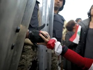A Lebanese anti-government protester holds the hand of a Lebanese army soldier as she blocks a road leading to the parliament in the capital Beirut's downtown district on January 27, 2020. PATRICK BAZ / AFP