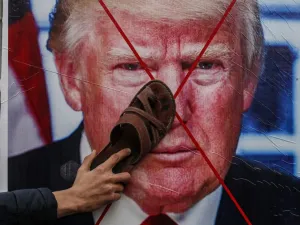 A Palestinian protester sticks his footwear on a poster depicting the face of US President Donald Trump during a demonstration against Trump's Middle East peace proposal in Khan Yunis in the southern Gaza Strip on February 3, 2020. SAID KHATIB / AFP