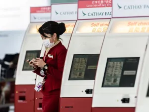 In this file photo taken on March 15, 2017, a mask-clad Cathay Pacific employee walks past a row of self check-in counters at the international airport in Hong Kong. AFP