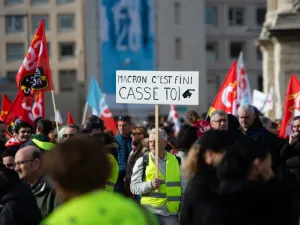 A protester wearing a yellow vest holds a sign reading "Macron, it's over, go away" as he takes part in a demonstration against the French government's plan to overhaul the country's retirement system in Marseille, southeastern France, on February 6, 2020. CLEMENT MAHOUDEAU / AFP