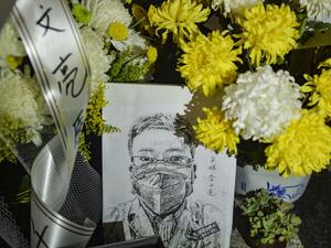 This photo taken on February 7, 2020 shows a photo of the late ophthalmologist Li Wenliang with flower bouquets at the Houhu Branch of Wuhan Central Hospital in Wuhan in China's central Hubei province. AFP