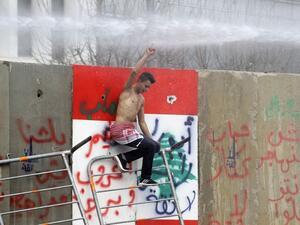 An anti-government protester climbs cement blocks protecting state institutions in central Beirut during protests on February 11, 2020 to stop a confidence vote for a new government, which they say fails to address their demands and cannot rescue the ailing country. Security forces used tear gas and water cannon to break up groups of demonstrators who hurled rocks at them and over the blast walls erected around parliament. Some lawmakers spent the night in parliament to thwart protesters who have successful