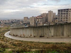 A picture taken on February 11, 2020 shows the Israeli settlement of Pisgat Zeev (L), built in a suburb of the mostly Arab east Jerusalem, and the Palestinian Shuafat refugee camp (R) behind Israel's controversial separation wall. AHMAD GHARABLI / AFP