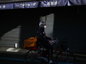 A postman rides his bicycle down a street in Tokyo's Tsukiji area on February 17, 2020. Japan said on February 17 it would cancel a public gathering to celebrate the birthday of new Emperor Naruhito on February 23, as fears grow over the spread of the new coronavirus in the country. CHARLY TRIBALLEAU / AFP