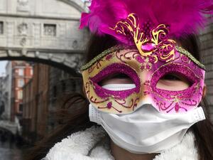 A young tourist wearing a protective facemask and a Carnival mask visits the streets of Venice, on February 24, 2020 during the usual period of the Carnival festivities which the last two days have been cancelled due to an outbreak of the COVID-19 the novel coronavirus, in northern Italy. Italy reported on February 24, 2020 its fourth death from the new coronavirus, an 84-year old man in the northern Lombardy region, as the number of people contracting the virus continued to mount. ANDREA PATTARO / AFP