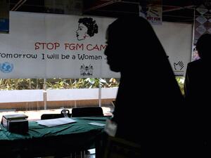 A young woman walks past a banner against female genital mutilation (AFP Photo/SIMON MAINA)