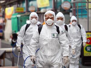 South Korean soldiers wearing protective gear spray disinfectant as part of preventive measures against the spread of the COVID-19 coronavirus, at a market in Daegu on March 2, 2020. South Korea reported nearly 500 new coronavirus cases on March 2, sending the largest national total in the world outside China past 4,000. YONHAP / AFP