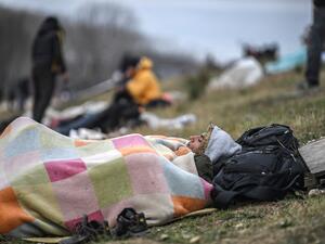 A migrant rests on the grass verge as they gather near the Tunca river waiting to resume their efforts to enter Europe near Pazarkule border gate in the city of Edirne, northwest Turkey on March 5, 2020. EU members on March 4, 2020 rejected what they said is Turkey's use of desperate migrants to pressure its neighbours -- and strongly backed Greece's border crackdown. The EU has scrambled to respond to the surge of migrants at the Greek border, where authorities say some 24,000 were stopped from entering be