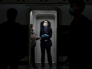A train attendant wearing a facemask as a preventive measure against the spread of the COVID-19 coronavirus assists a passenger at the Changsha railway station in Changsha, the capital of Hunan province on March 5, 2020. More than 95,000 people have been infected and over 3,200 have died worldwide from the new coronavirus, which by on March 5 had reached some 80 countries and territories. Noel CELIS / AFP