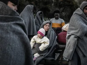 Migrants and refugees who arrived from Turkey to the Greek island of Lesbos on March 5, try to keep warm as they gather in the yard of a small church where they have spent the rainy night near Skala Sykamnias on March 6, 2020. A group of 42 refugees and migrants weave through coast guard patrols and arrived on the shores of Lebos during the evening of March 5. LOUISA GOULIAMAKI / AFP