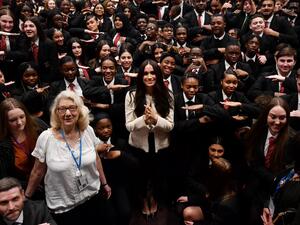 Britain's Meghan, Duchess of Sussex poses with school children making the 'Equality' sign following a school assembly during a visit to Robert Clack School in Essex, on March 6, 2020, in support of International Women’s Day. BEN STANSALL / POOL / AFP