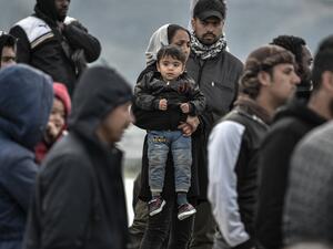 Refugees and migrants who arrived on Lesbos island after March 1, stand in the port of Mytilene next to the military carrier which accomodates them on the island of Lesbos on March 7, 2020. Over 1,700 migrants have landed on Lesbos and four other Aegean islands from Turkey over the past week, adding to the 38,000 already crammed into abysmal and overstretched refugee centres. LOUISA GOULIAMAKI / AFP