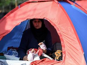 A woman and her baby are pictured in a tent at a migrants' makeshift camp near a bus terminal, as they wait to resume their efforts to enter Europe near Pazarkule border gate in the city of Edirne, northwest Turkey on March 8, 2020. EU members on March 4, 2020 rejected what they said is Turkey's use of desperate migrants to pressure its neighbours -- and strongly backed Greece's border crackdown. The EU has scrambled to respond to the surge of migrants at the Greek border, where authorities say some 24,000 