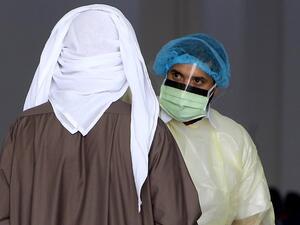 Kuwaiti healthy ministry workers scan expatriates living in Kuwait who returned from Egypt, Syria and Lebanon, as they arrive to a specified place to be tested for coronavirus in Kuwait City on March 12, 2020. YASSER AL-ZAYYAT / AFP