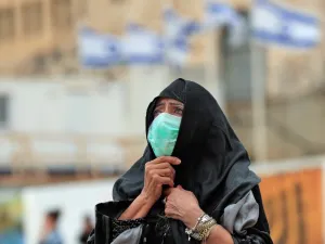 A woman, wearing a protective mask, looks at the nearly deserted Western Wall, Judaism's holiest site, after Israel has imposed some of the world's tightest restrictions to contain COVID-19 coronavirus disease, in Jerusalem on March 12, 2020. Israel imposed a two-week quarantine on all travellers entering the country, almost stopping tourism and limiting public gatherings as officials confirmed its 100th case of the COVID-19 coronavirus disease. Emmanuel DUNAND / AFP