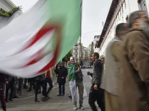 An Algerian protester waves the national flag during a weekly anti-government demonstration in the capital Algiers on March 13, 2020. Algeria has registered two deaths from the novel coronavirus, the health ministry announced, as schools were closed for three weeks. RYAD KRAMDI / AFP