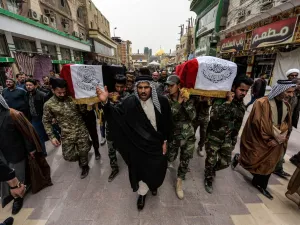 Mourners walk with a coffin draped with the Iraqi national flag defaced with text in Arabic reading "Holy Imam Ali Shrine" during a funerary march for members of the Hashed al-Shaabi (Popular Mobilisation Forces) paramilitaries who were killed in an area targeted by US military air strikes, in the central Iraqi holy shrine city of Najaf on March 14, 2020. AFP/File