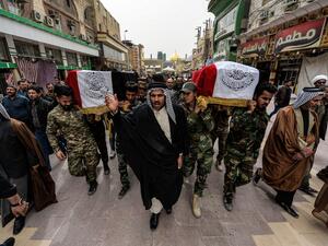 Mourners walk with a coffin draped with the Iraqi national flag defaced with text in Arabic reading "Holy Imam Ali Shrine" during a funerary march for members of the Hashed al-Shaabi (Popular Mobilisation Forces) paramilitaries who were killed in an area targeted by US military air strikes, in the central Iraqi holy shrine city of Najaf on March 14, 2020. AFP/File