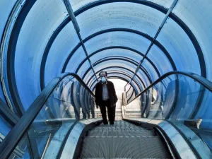 A man wearing a protective face mask rides the escalator of a pedestrian overpass bridge in Iran's capital Tehran on March 14, 2020. STRINGER / AFP