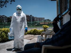 A laboratory specialist wearing protective gear speaks with a man asking to get tested in front of the ward for quarantined people who had close contacts with the first Kenyan patient of the COVID-19 at the Infectious Disease Unit of Kenyatta National Hospital in Nairobi, Kenya, on March 15, 2020. AFP